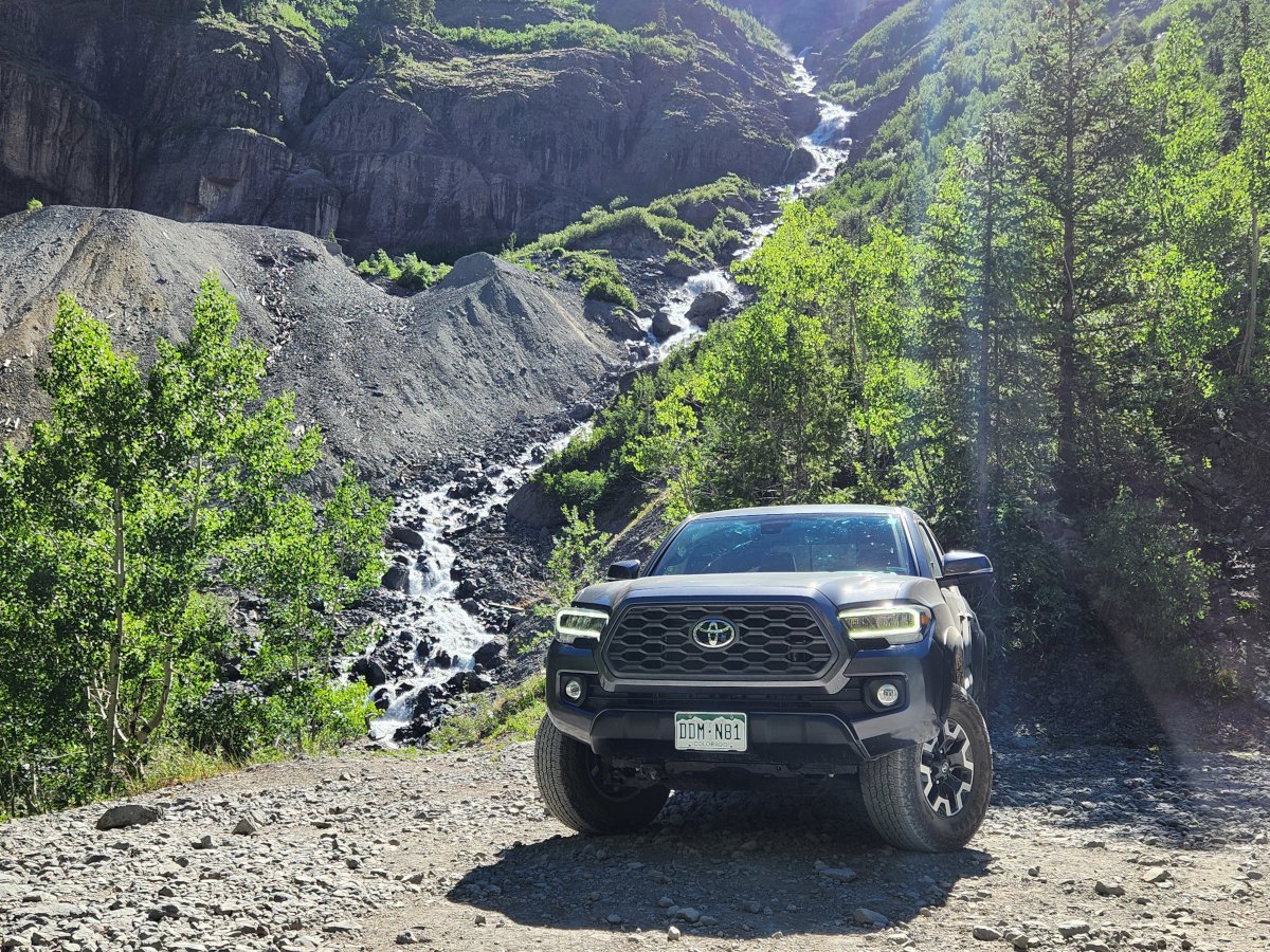 toyota tacoma on trail with stream in background